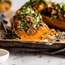 Sliced rice, lentil and kale stuffed butternut squash on a parchment paper-lined baking tray.