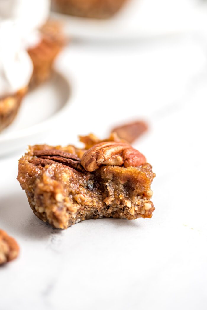 Close up of a mini vegan no-bake pecan pie tart with a bite taken out of it.