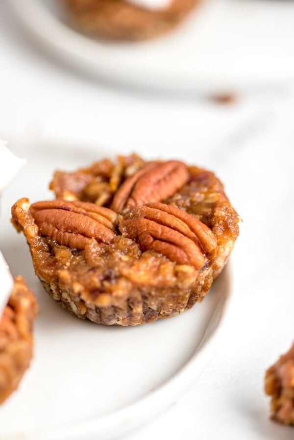 Mini no-bake pecan pie tart topped with 3 pecans on a small plate.