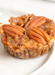 Mini no-bake pecan pie tart topped with 3 pecans on a small plate.