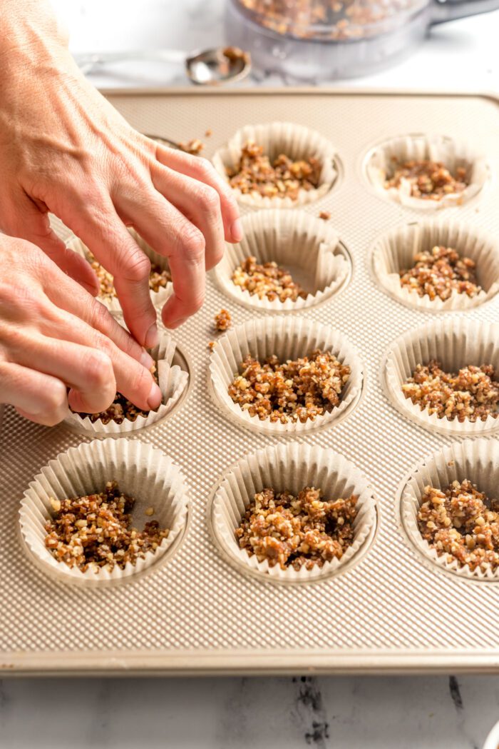 Pressing dough down into a cupcake liner-lined 12 piece muffin tin.