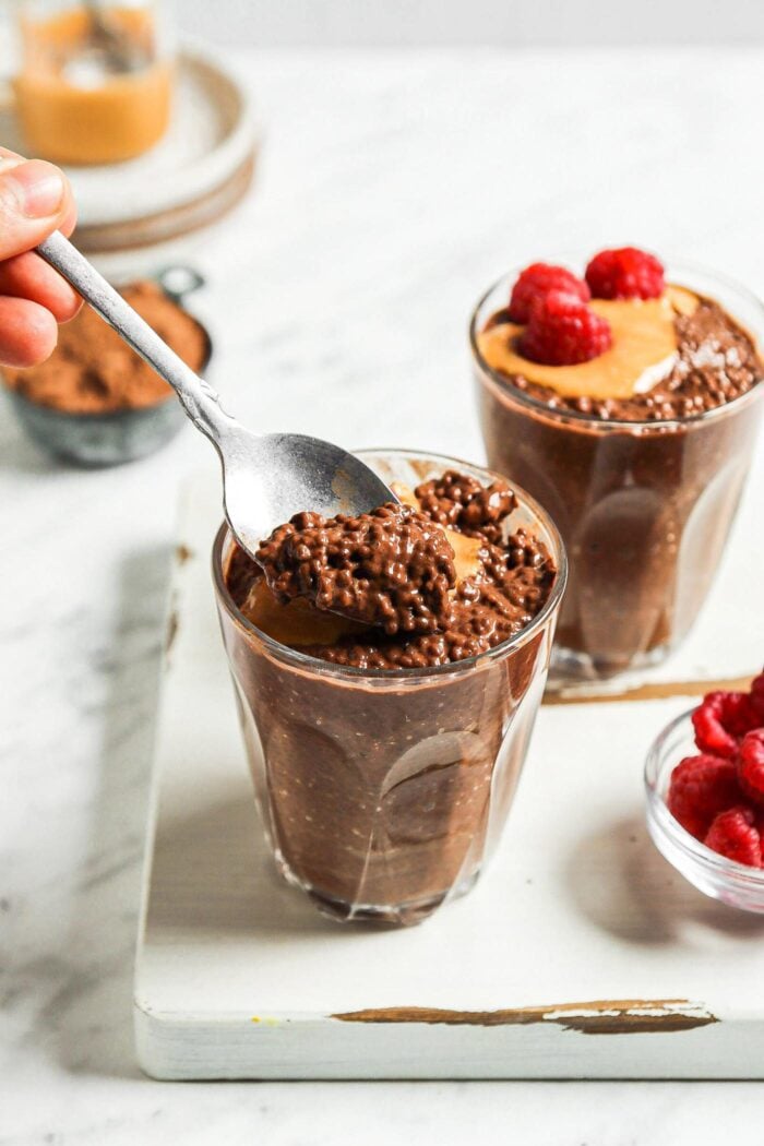 Scooping chocolate chia seed pudding from a small glass.