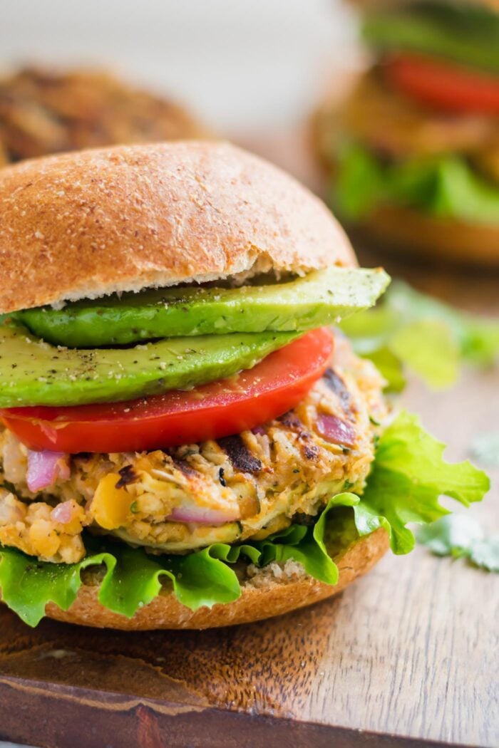 Close up of a veggie burger on a toasted bun topped with lettuce, tomato and avocado.