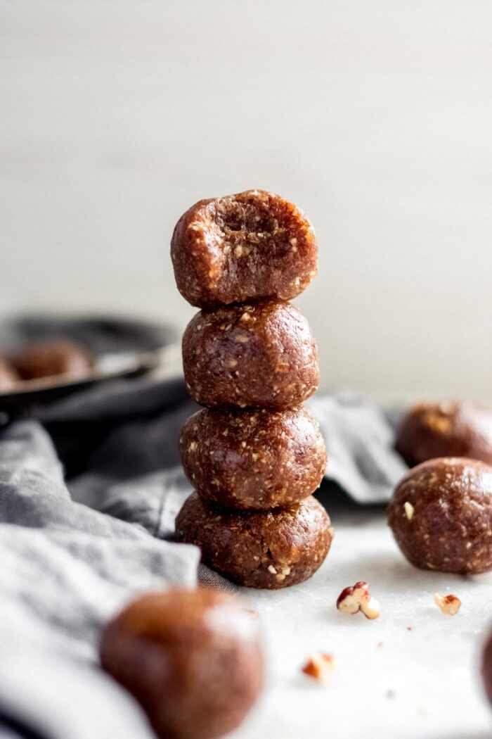 Stack of 4 pecan pie energy balls, one on top has a bite taken out of it.
