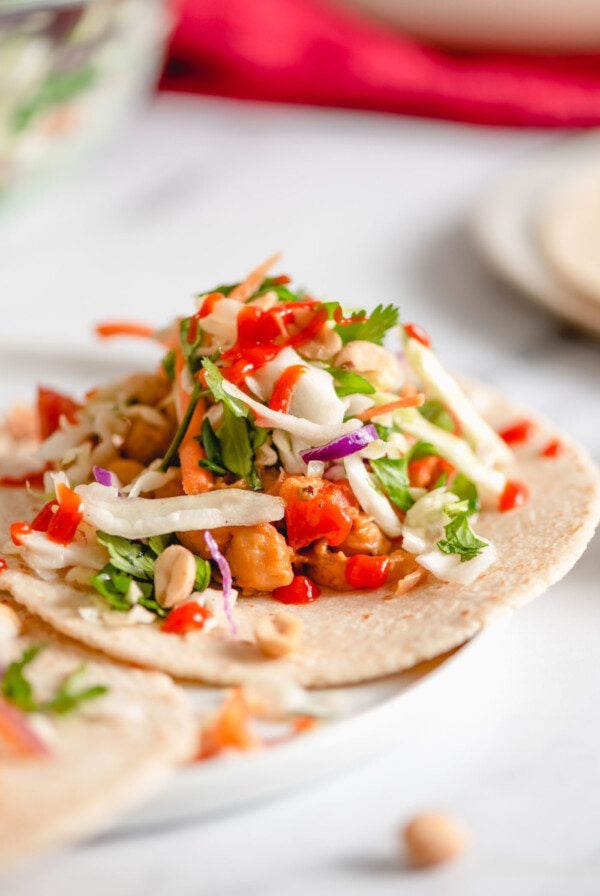 Tacos with a spicy peanut and bell pepper chickpea filling topped with cabbage slaw and hot sauce.