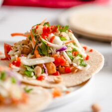 Tacos with a spicy peanut and bell pepper chickpea filling topped with cabbage slaw and hot sauce.