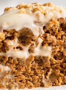 Slice of double layered carrot cake topped with walnuts.