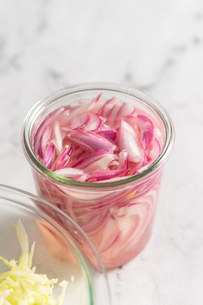 A jar of thinly sliced pickled red onions.