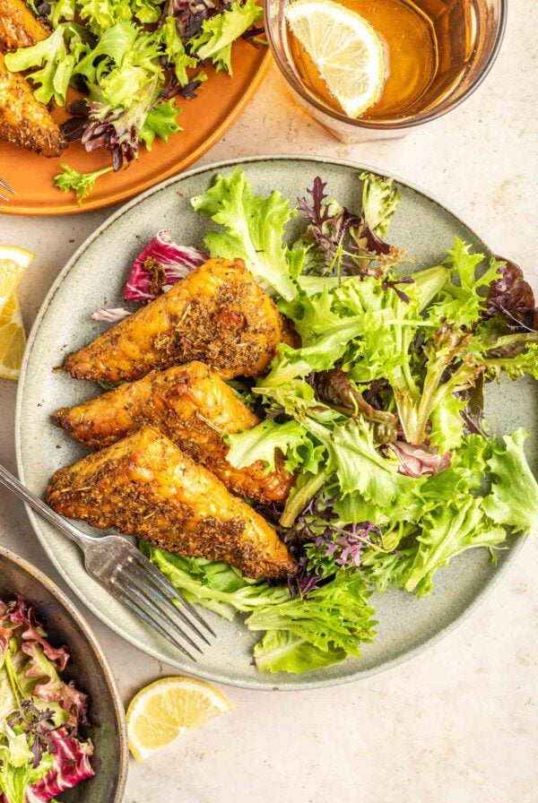 3 pieces of garlic herb marinated baked tempeh on a plate with a green salad and fork.