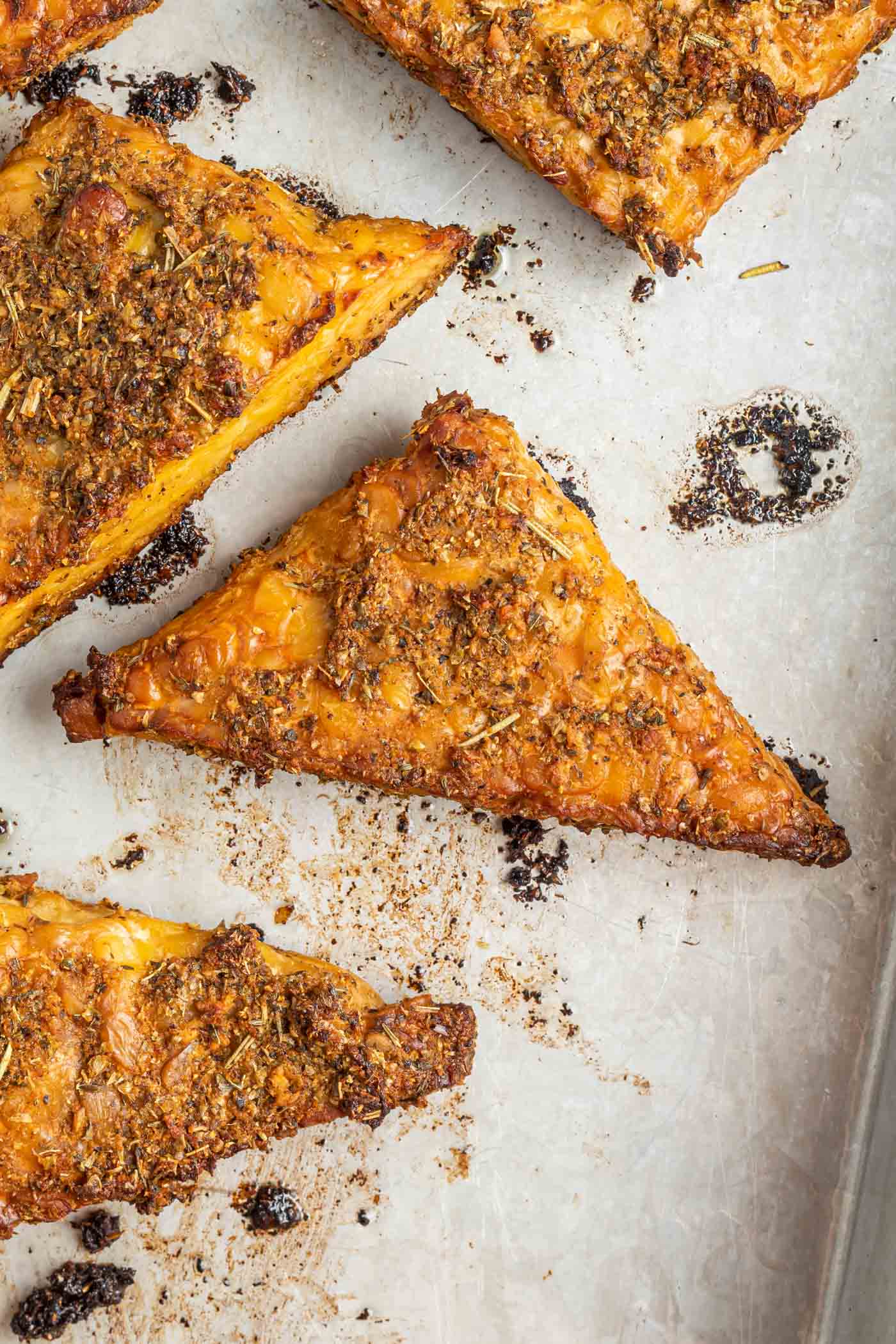 A triangle of golden brown garlic herbed marinated baked tempeh on a baking tray.