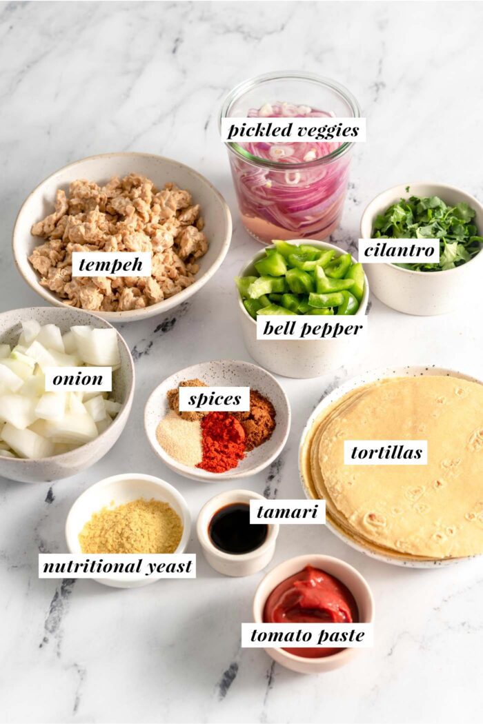 All ingredients needed for making a vegan tempeh taco recipe. Each ingredient is labelled with text.