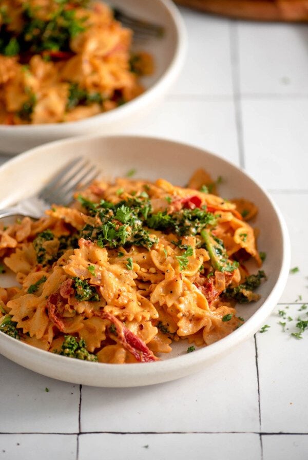 A bowl of creamy sun dried tomato pasta with kale.