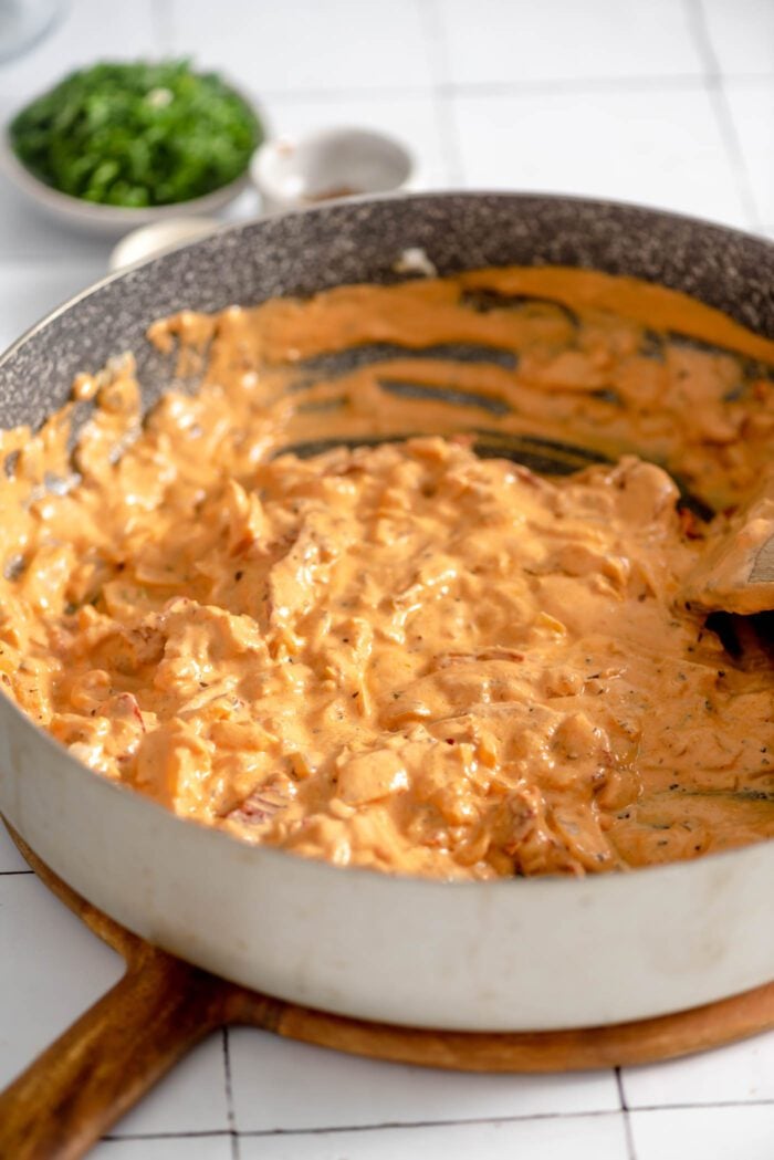 Thick and creamy sun-dried tomato pasta sauce cooking in a large skillet.