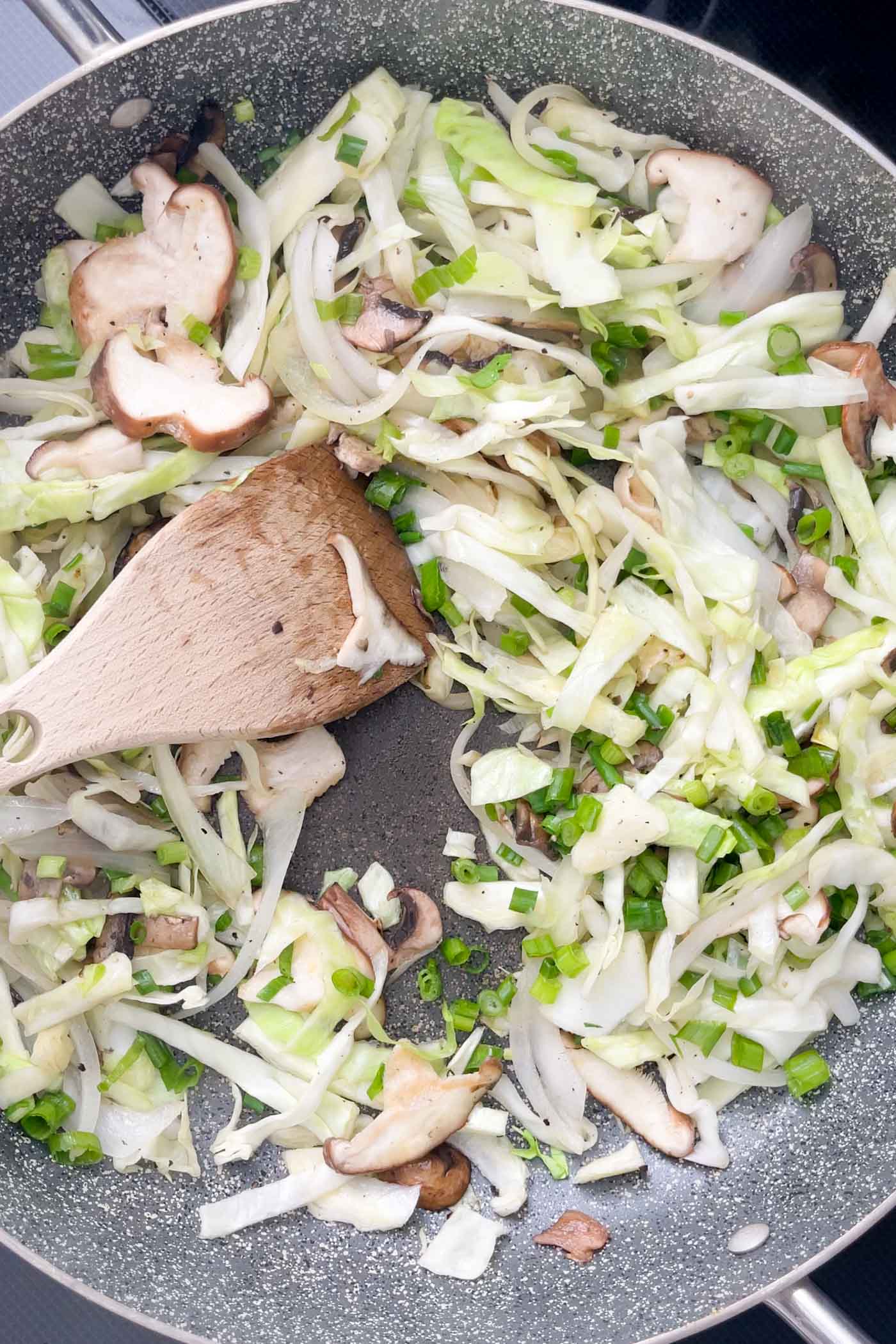 Stir fried cabbage, onion and mushroom cooking in a skillet.