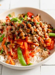 Chickpeas in teriyaki sauce served over stir fried vegetables and rice and topped with scallions and sesame seeds.