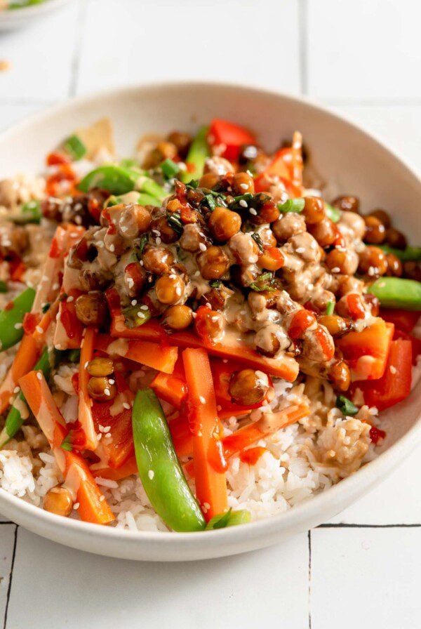 Chickpeas in teriyaki sauce served over stir fried vegetables and rice and topped with scallions and sesame seeds.