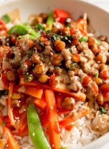 Chickpeas in teriyaki sauce served over stir fried vegetables and rice and topped with scallions and sesame seeds.