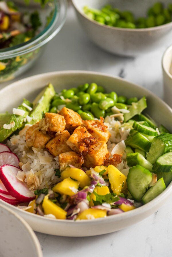 Colourful tofu bowl with mango salsa, edamame, avocado, cucumber, radish and sweet chili tofu.