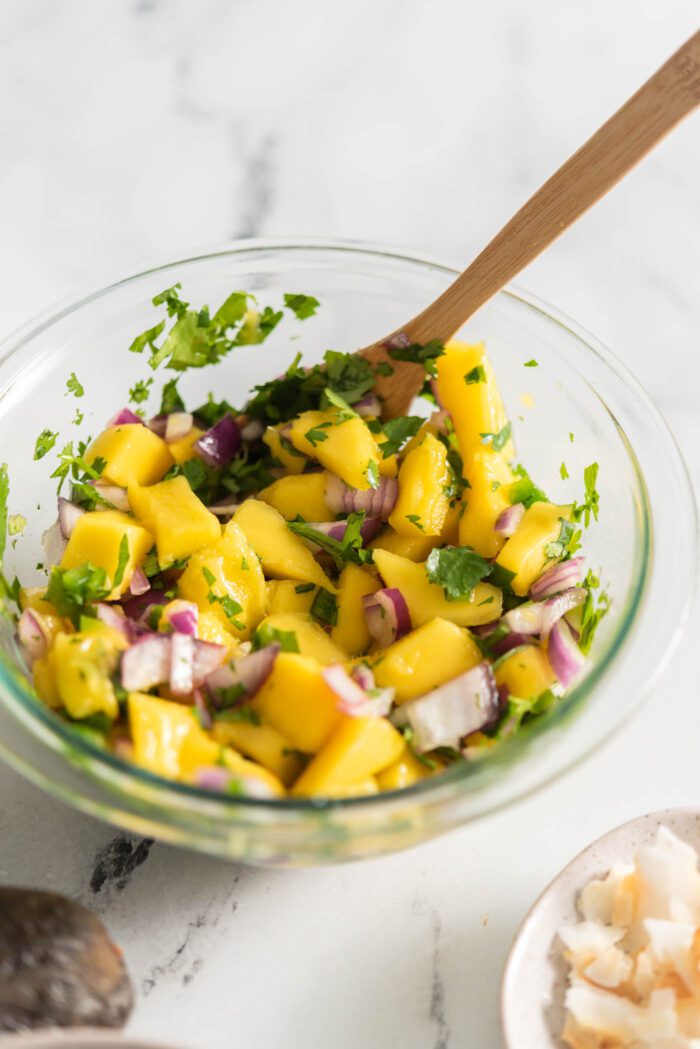 Mango salsa with red onion, cilantro and jalapeno in a small bowl.