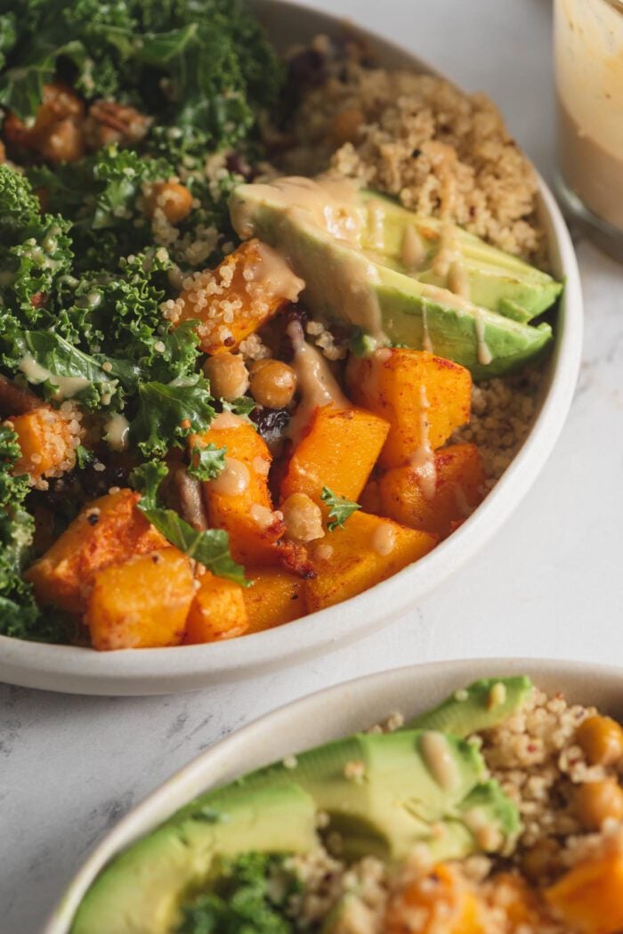 Close up of roasted butternut squash in a bowl with quinoa, avocado, cranberries and pecans.