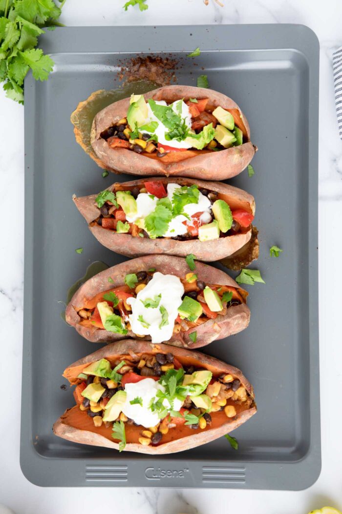 Baked sweet potatoes stuffed with a black bean, red pepper and corn filling and topped with sour cream, avocado and cilantro.