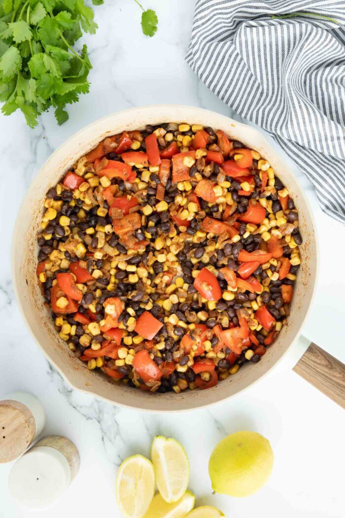 Black beans, corn and bell pepper cooked in spices in a large skillet.