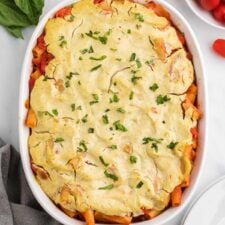 Overhead view of baked ziti sprinkled with fresh herbs in an oval baking dish/