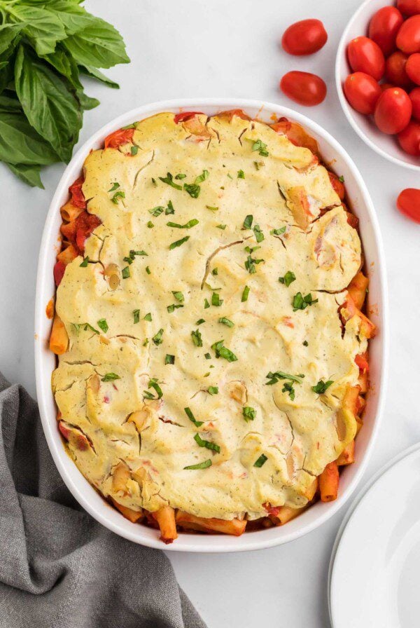 Overhead view of baked ziti sprinkled with fresh herbs in an oval baking dish/