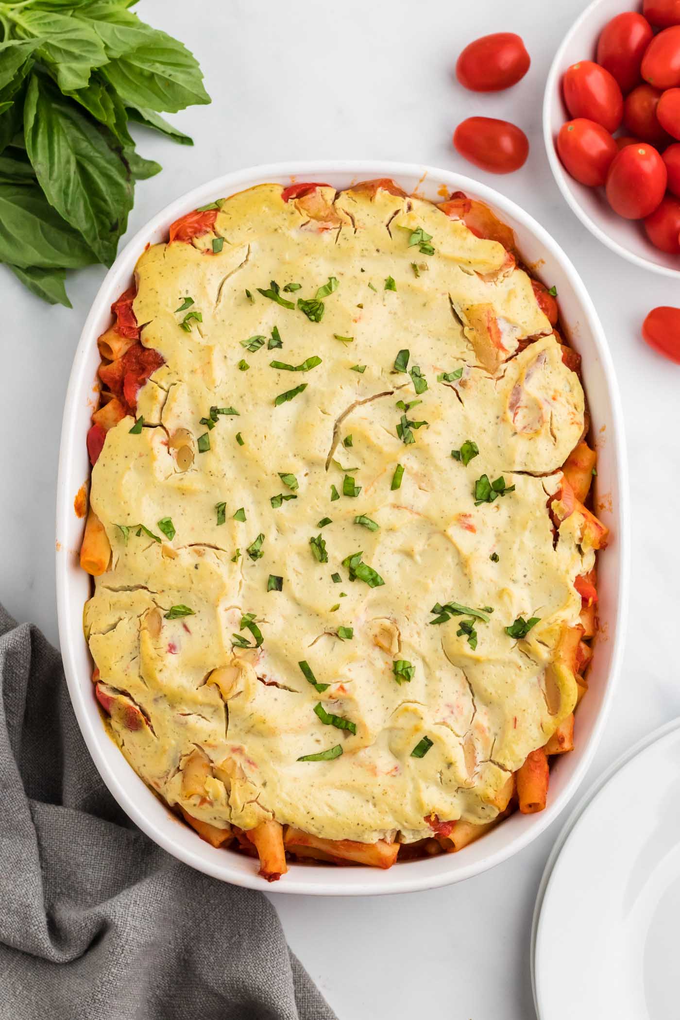 Overhead view of baked ziti sprinkled with fresh herbs in an oval baking dish/