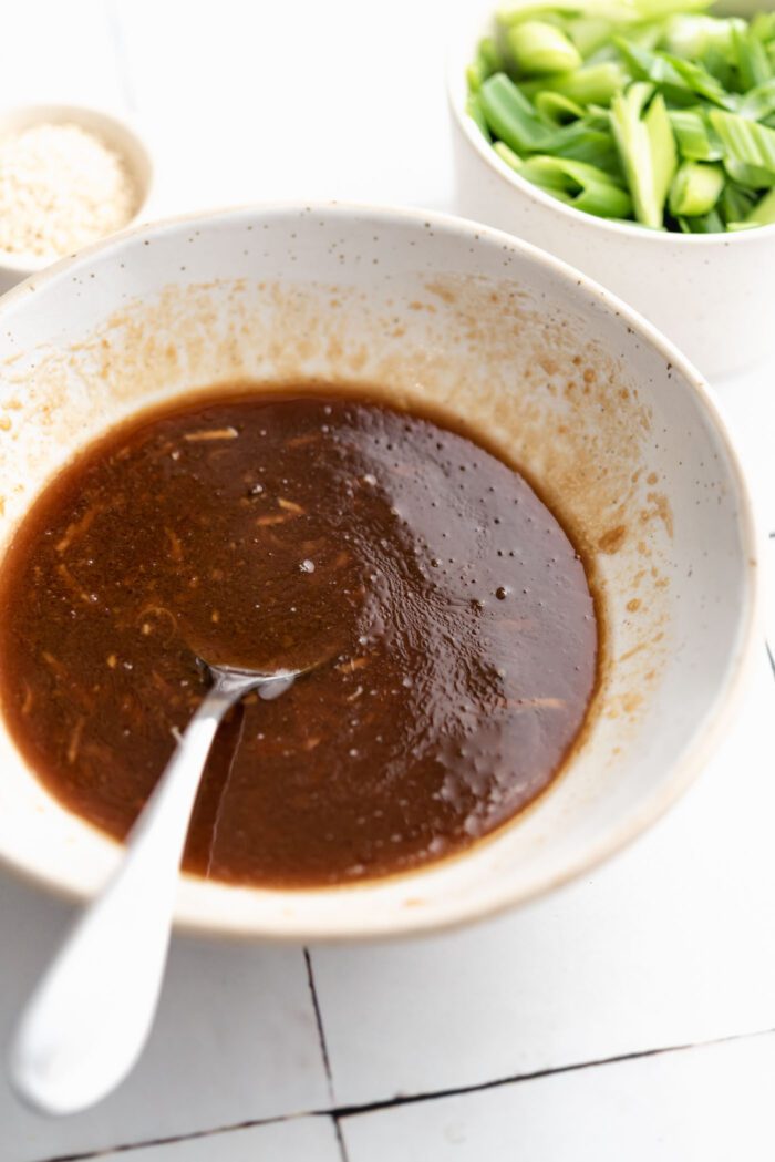 Sesame miso garlic sauce mixed together in a small bowl. A spoon rests in the bowl.
