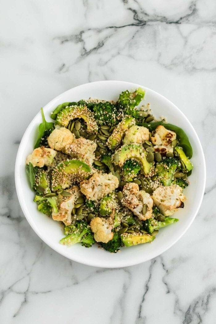 Healthy broccoli and cauliflower salad with avocado, hemp seeds and sesame seeds in a bowl.