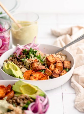 A colourful, healthy bowl with quinoa, tofu, sweet potato, lentils, avocado and kale.