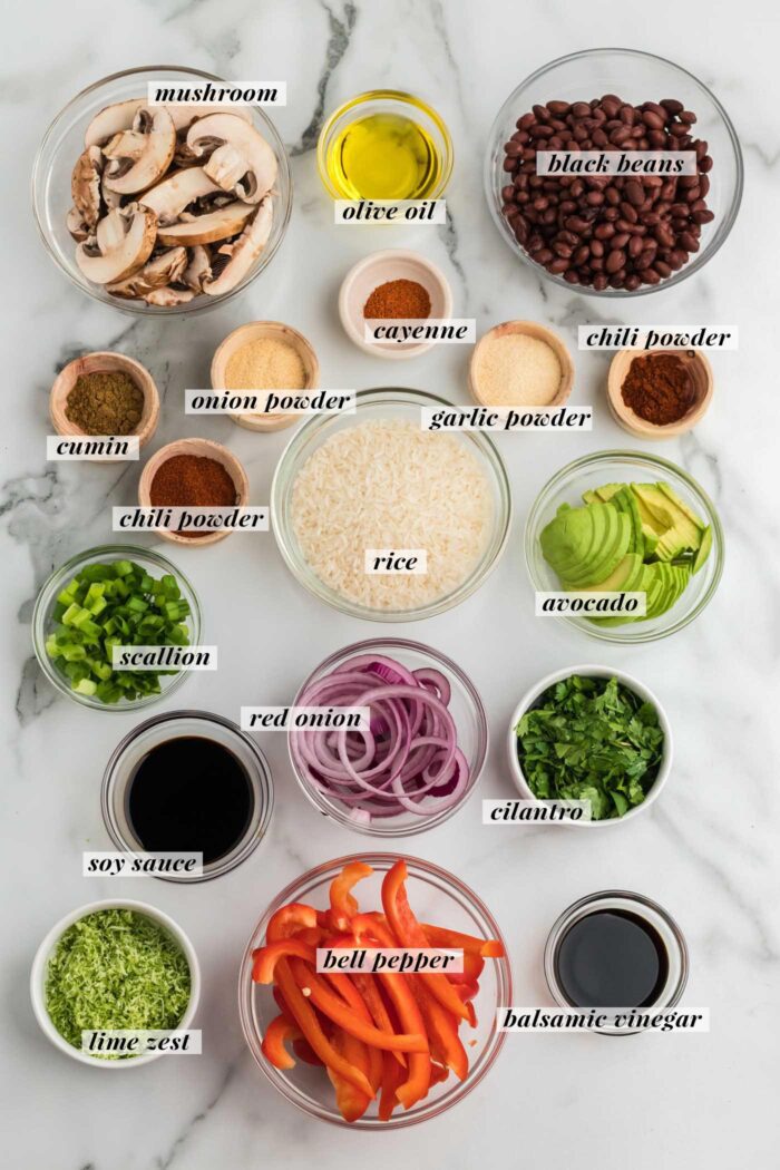 All the ingredients mise en place for making vegetarian fajita bowls with spices, mushrooms, peppers, onions and black beans.
