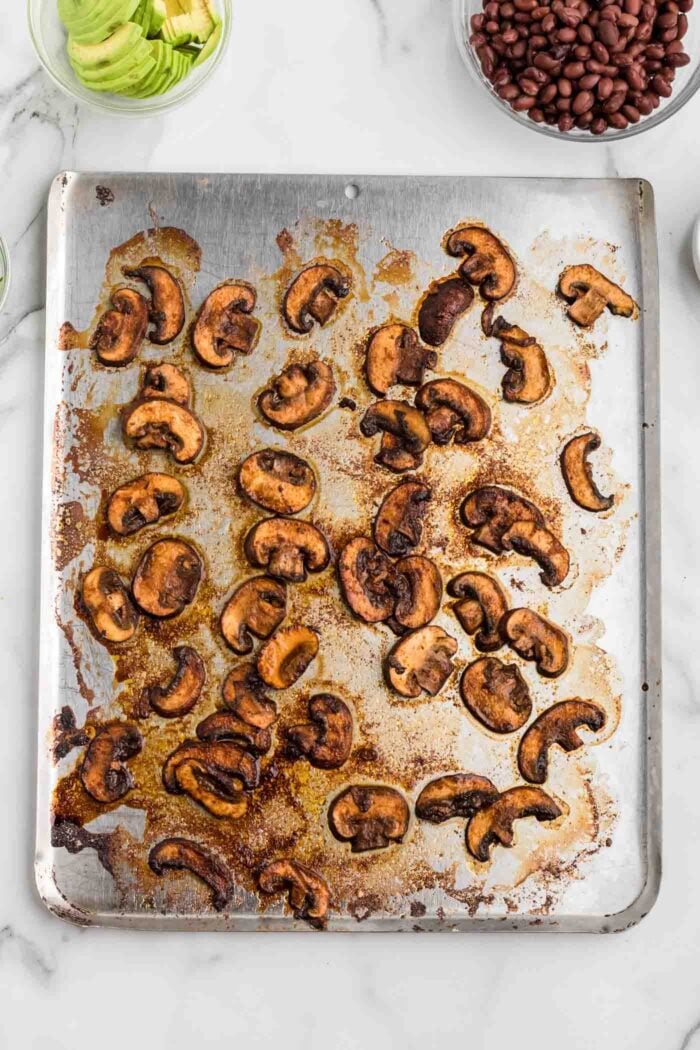 Marinated sliced and roasted mushrooms on a baking tray.
