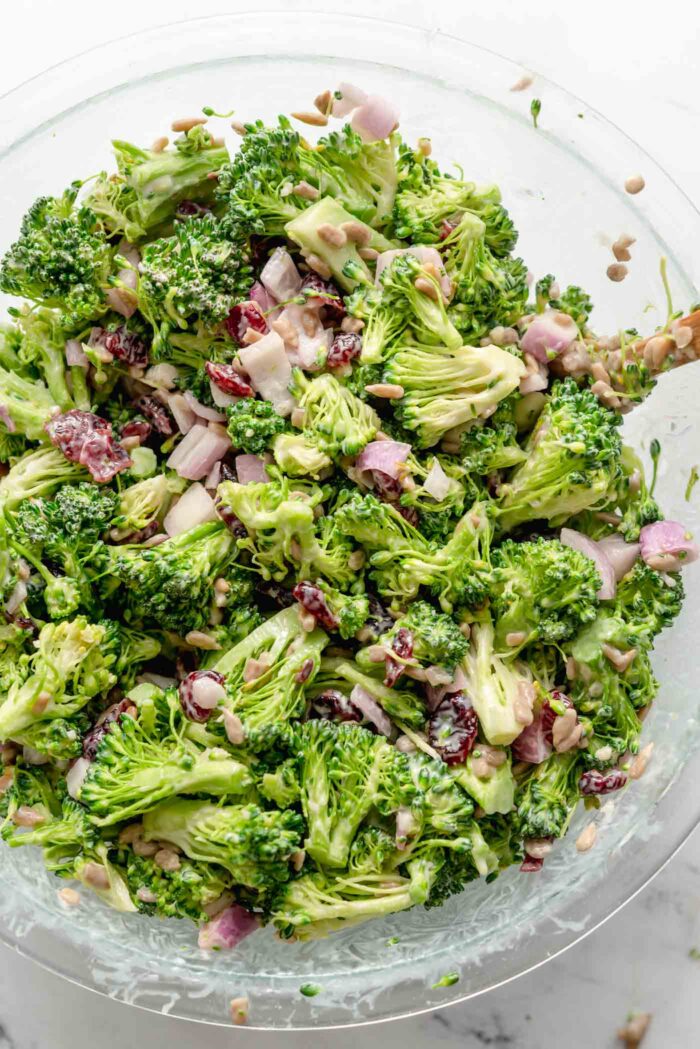 Overhead view of a large bowl of creamy vegan broccoli salad with cranberries, red onion and sunflower seeds