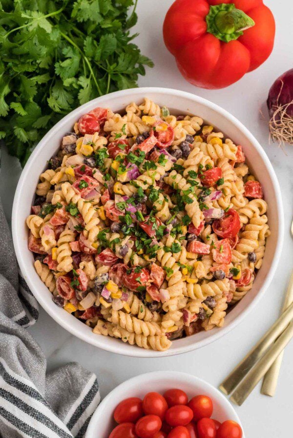 Overhead view of a large bowl of vegan southwest pasta salad with cilantro, black beans, corn, bell pepper and chipotle dressing..