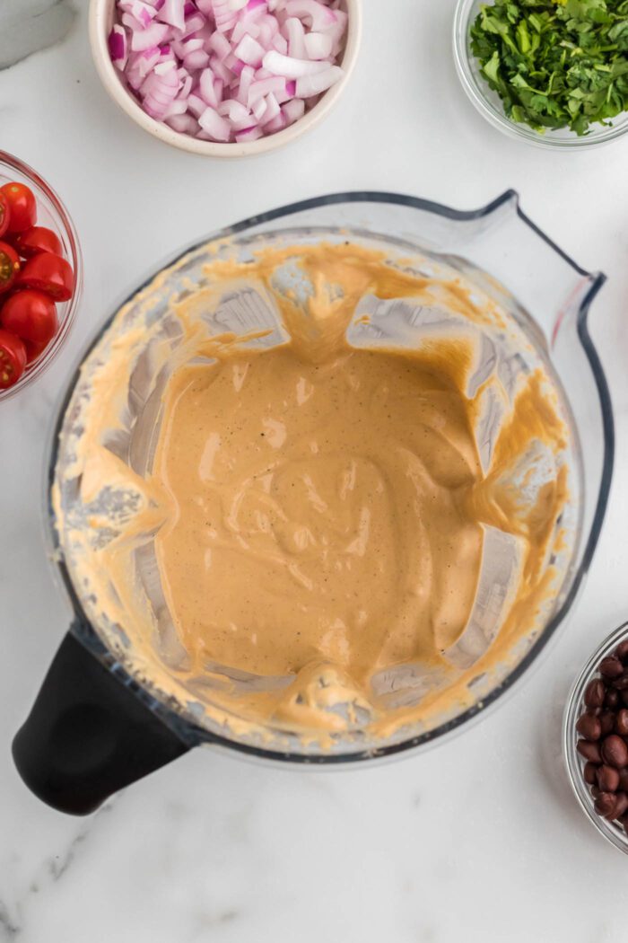 Overhead view into a blender container with a creamy cashew chipotle dressing.