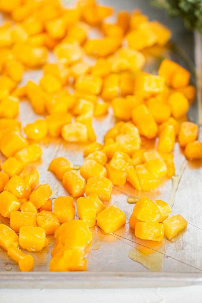 Cubes of roasted butternut squash on a baking tray.