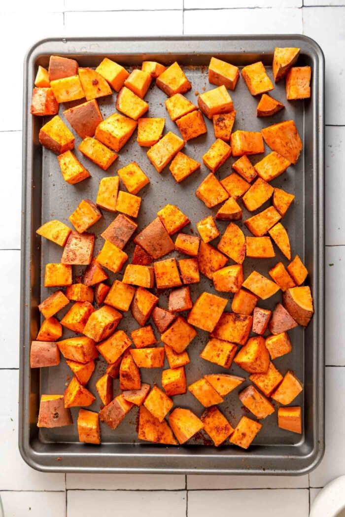 Sweet potato cubes coated in taco spices on a baking tray.