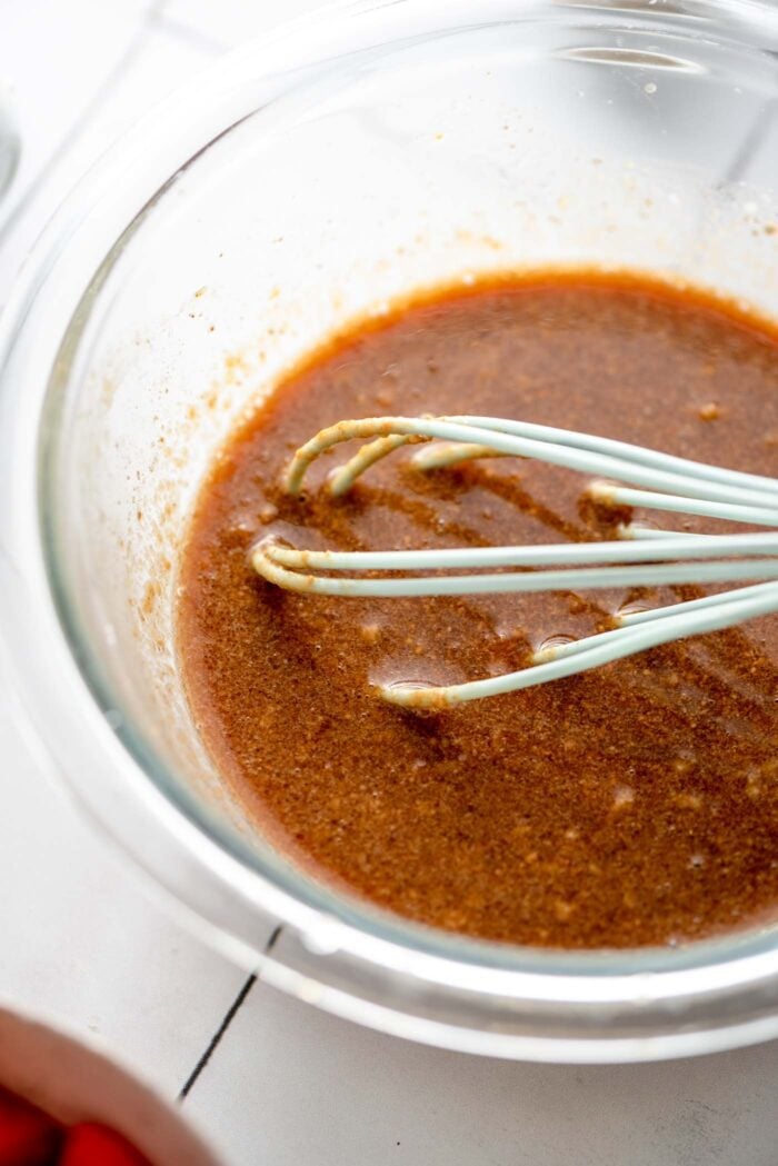 Stir fry sauce mixed up in a small glass mixing bowl with a whisk resting in the bowl.