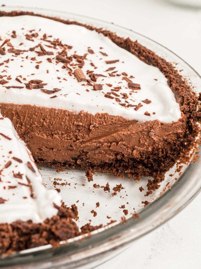 Close up of a chocolate pie with chocolate crust in a pie dish with once slice removed so you can see the inside texture of the pie.