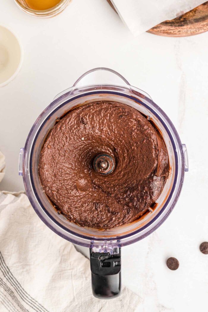 A creamy chocolate pie filling mixture in a food processor container.