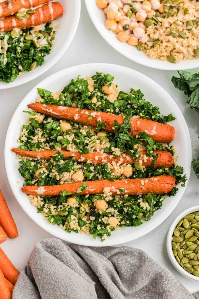 Mixed kale quinoa chickpea salad with roasted carrots, pumpkin seeds and tahini sauce.