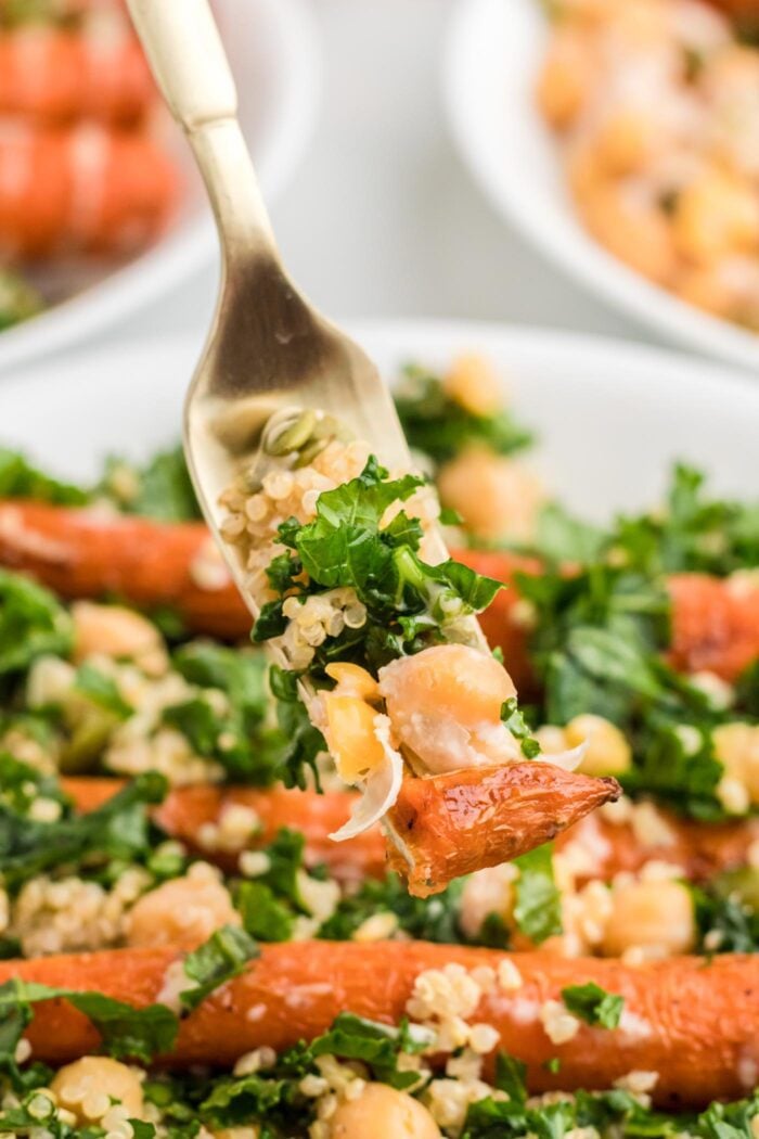 Forkful of kale, carrot and quinoa held over a kale quinoa chickpea salad.