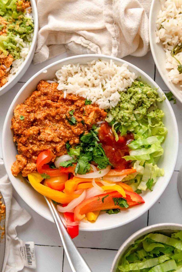 Tofu sofritas burrito bowl with rice, guacamole, cilantro, lettuce and cooked peppers and onions.