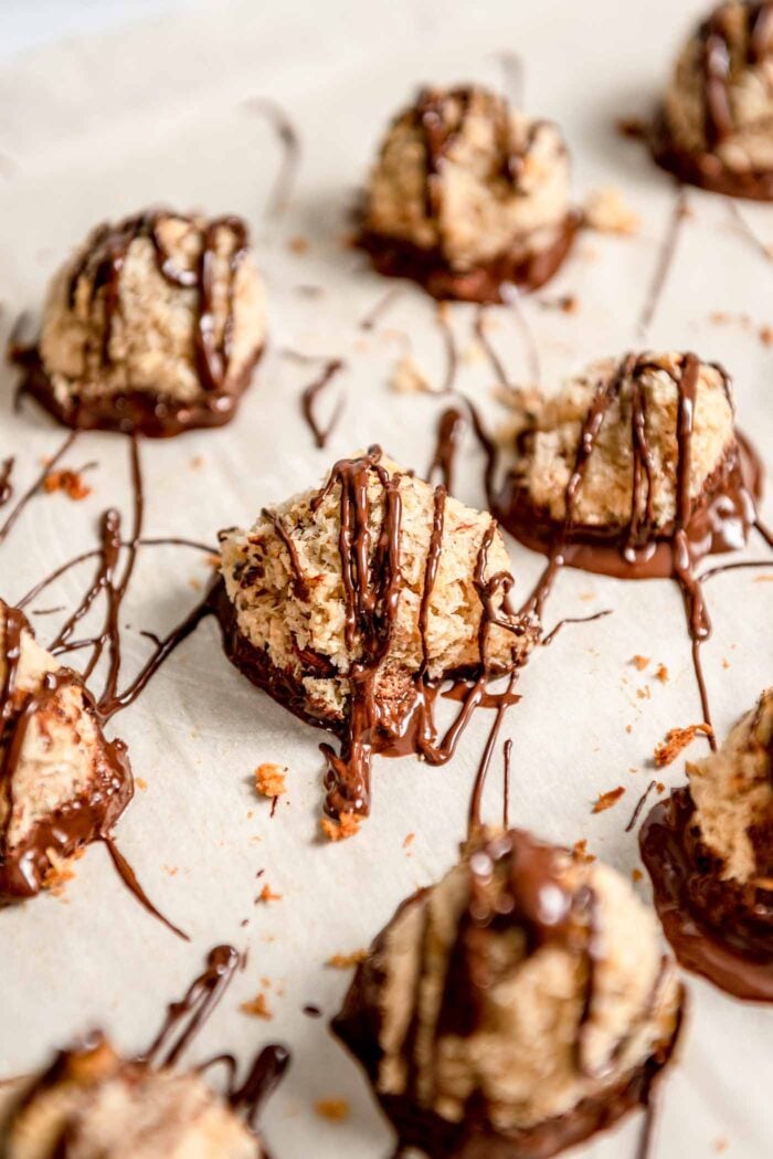 Almond macaroons drizzled with melted chocolate on a baking tray lined with parchment paper.