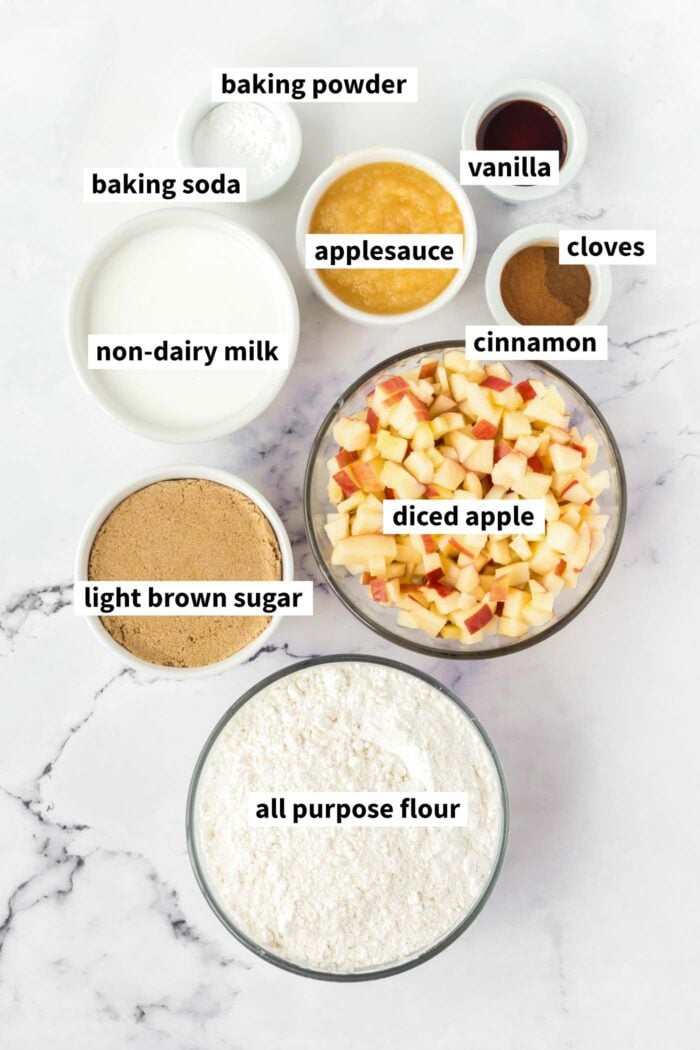 A visual ingredient list of the ingredients for vegan apple cake gathered in bowls and labelled with text.
