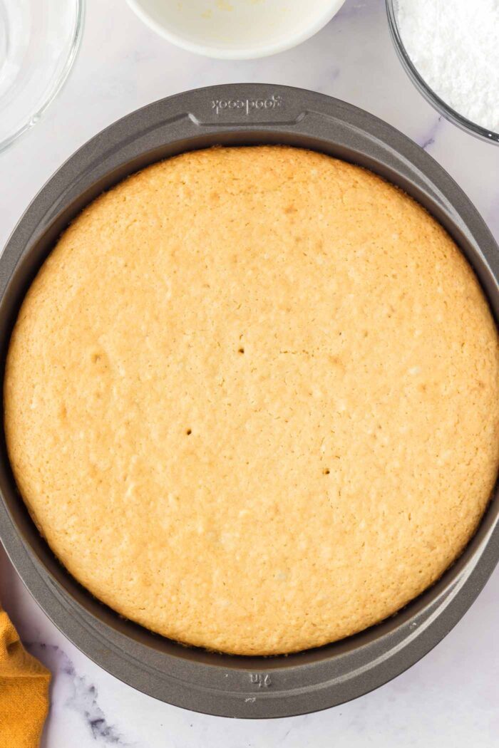 A baked olive oil cake in a round cake pan.