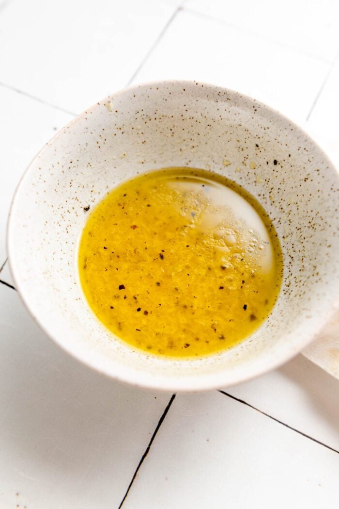 Lemon garlic olive oil vinaigrette mixed in a small dish on a counter.