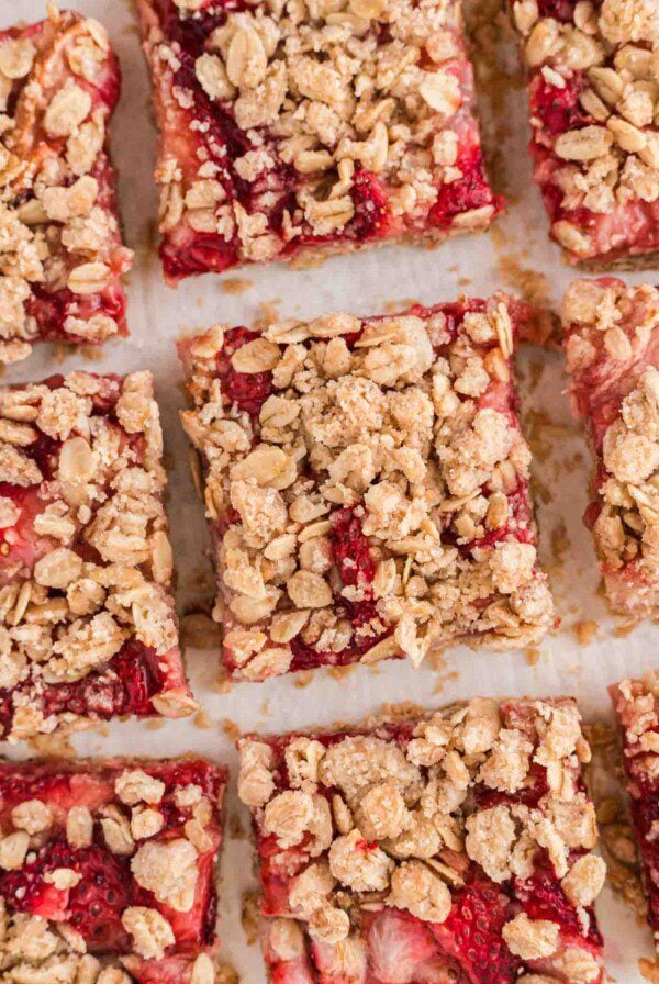 An overhead close up of a number of strawberry oat bars with an oatmeal crumble topping.